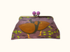 Large clutch purse with purple ball closure. patterned with orange-footed scrub fowls and leaves on a purple background