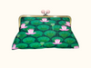 Clutch purse with pale pink ball closure and a pattern of pink sacred lotus, seed pods and lily pads in blue-green tones
