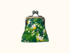 kisslock coin purse with yellow and white tamanu flowers on a green leafy background