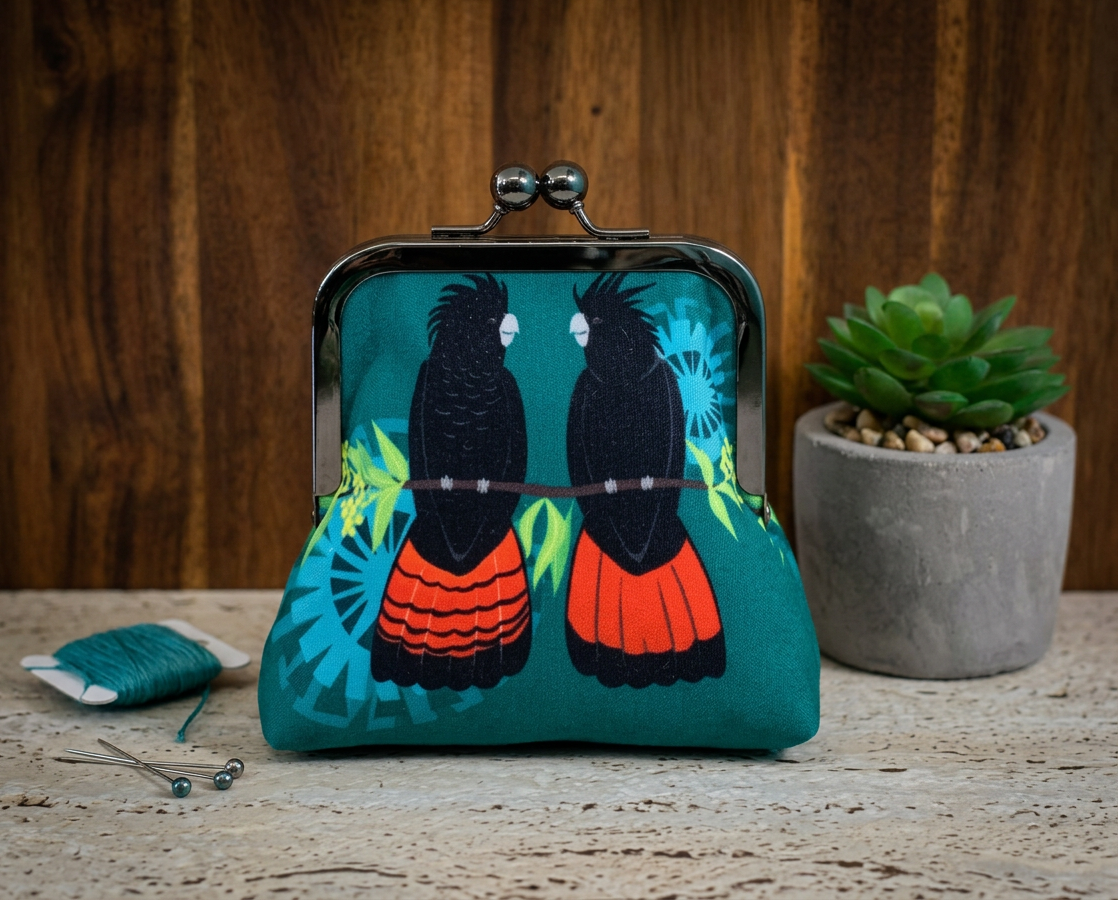 large kisslock purse printed two red-tailed black cockatoos sitting on a wattle branch