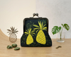 large kisslock purse with two bright mid-century modern inspired pineapples on a black background