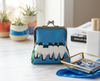 large kisslock coin purse with a row of white-breasted woodswallows bunched together on a branch against a blue background of falling leaves