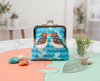 large kisslock coin purse with two zebra finches facing each other on a blue patterned background