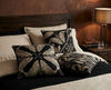 cushions with beige pattern of Atlas moth and Atlas Croton on a black background on a bed 