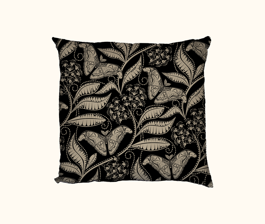 cushion with beige pattern of Atlas moth and Atlas Croton on a black background
