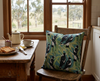 cushion with an all-over pattern of Australian magpies in a gum tree against a light blue-green background on a chair at a breakfast table