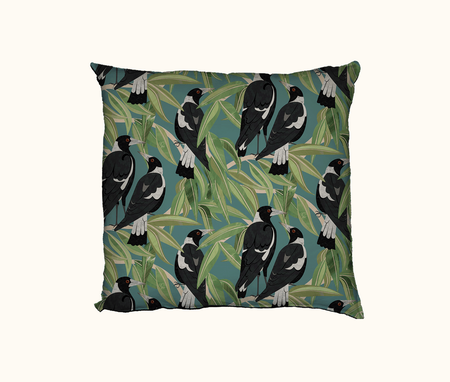 cushion with an all-over pattern of Australian magpies in a gum tree against a light blue-green background