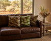 two cushions featuring an abstract design based on cycad seeds and trunks against a backdrop of fallen leaves on the woodland floor and a design featuring a repeat patten of the cycad plant on a leather lounge