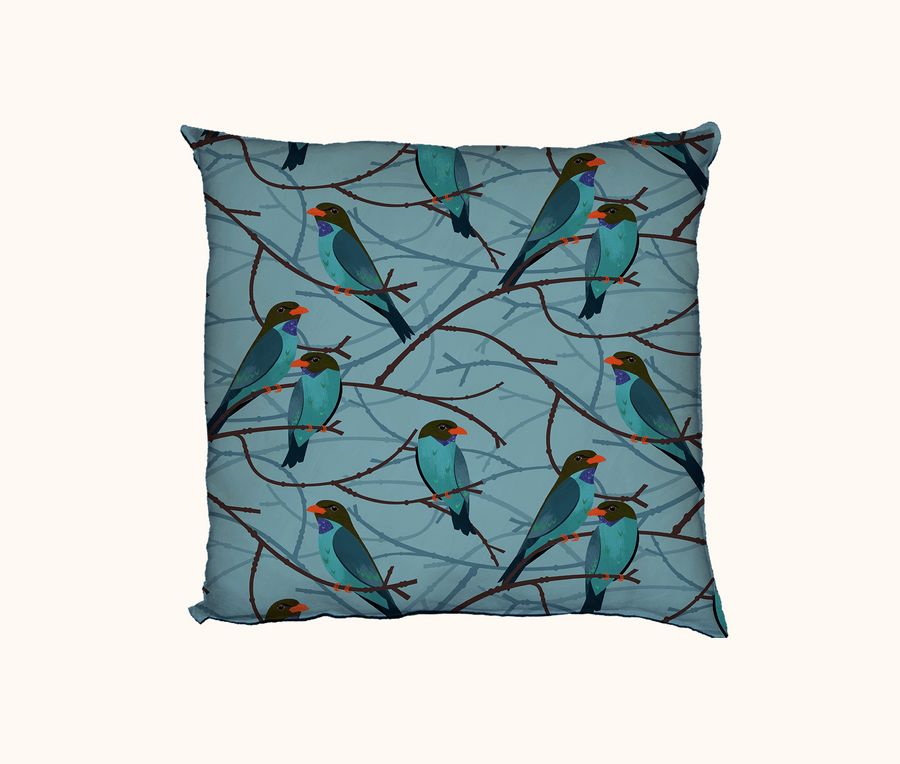 cushion with pattern of dollarbirds perched on twigs against a blue background