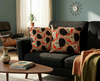 cushions printed with a flame-backed fiddler crab pattern in black and red-orange against a wavy beige background, with a mid-century modern feel in a lounge-room on a black couch