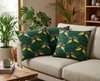 cushion featuring stylised Gouldian finches with red faces against a green and teal leafy background on a couch in a tropical  living room