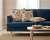 cushions featuring stylised limpet shells in browns, beige and an earthy orange tone on a blue sofa