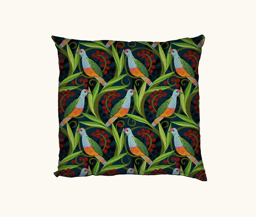 cushion with a pattern of rose-crowned fruit doves, leaves and berries on a dark blue background
