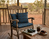 cushions patterned with highly stylised quolls in rows against a blue background on a wooden rocking chair on a verandah