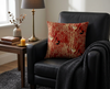 45cm cushion patterned with stylised red-backed fairywrens on speargrass against a red background in a black armchair near a coffee table