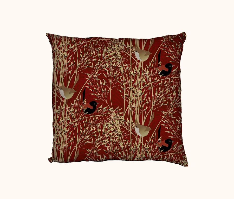 cushion patterned with stylised red-backed fairywrens on speargrass against a red background 