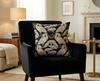 Cushion cover featuring black and cream pattern of royal spoonbills and sacred lotus leaves on a black armchair