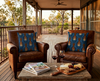 cushion featuring highly stylised silver-crowned friarbirds on a blue leaf-like pattern on leather chairs on a verandah