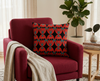 cushion featuring Sturt's desert pea flower on a background of diamonds and ovals in red, teal and black on a red chair