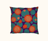 cushion with a bright abstract sundew pattern in reds and oranges, against a background of large irregular spots of teal on purple