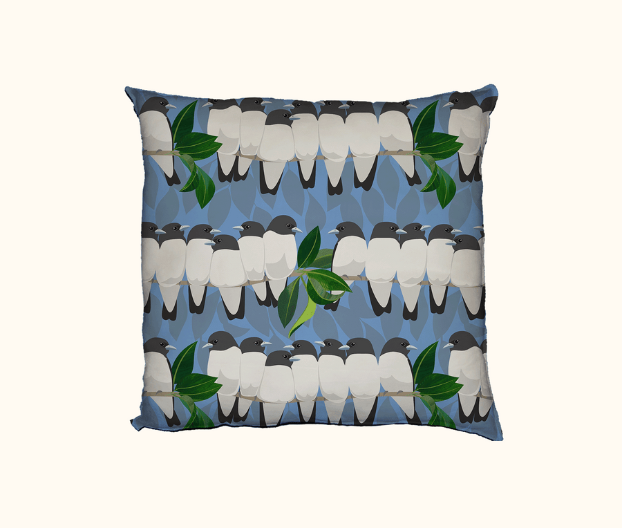 cushion with rows of white-breasted woodswallows on branches against a blue background of falling leaves