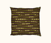 a cushion featuring an abstract design based on cycad seeds and trunks against a backdrop of fallen leaves on the woodland floor