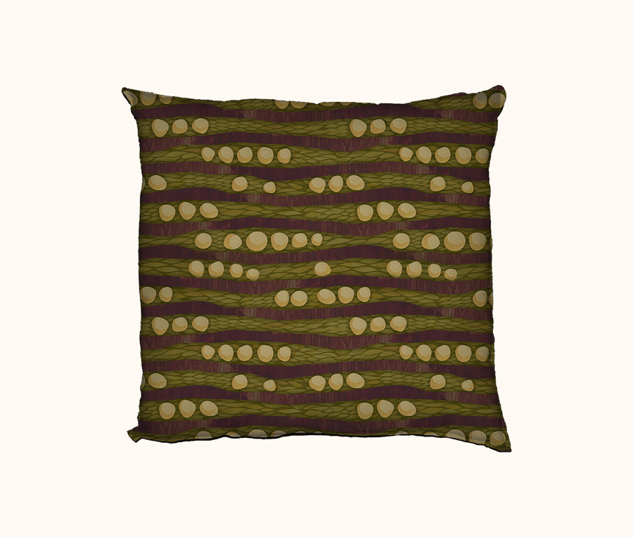 a cushion featuring an abstract design based on cycad seeds and trunks against a backdrop of fallen leaves on the woodland floor