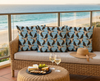 cushions with pattern of welcome swallows flying in different directions in rows, with a cloud pattern in the background on a rattan couch on a balcony overlooking the beach