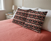 cushions with black, white and grey willie wagtail pattern on a coral background on  a bed with a coral bedspread