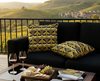 cushions with black, white and grey willie wagtail pattern on a yellow background on a black couch on a balcony