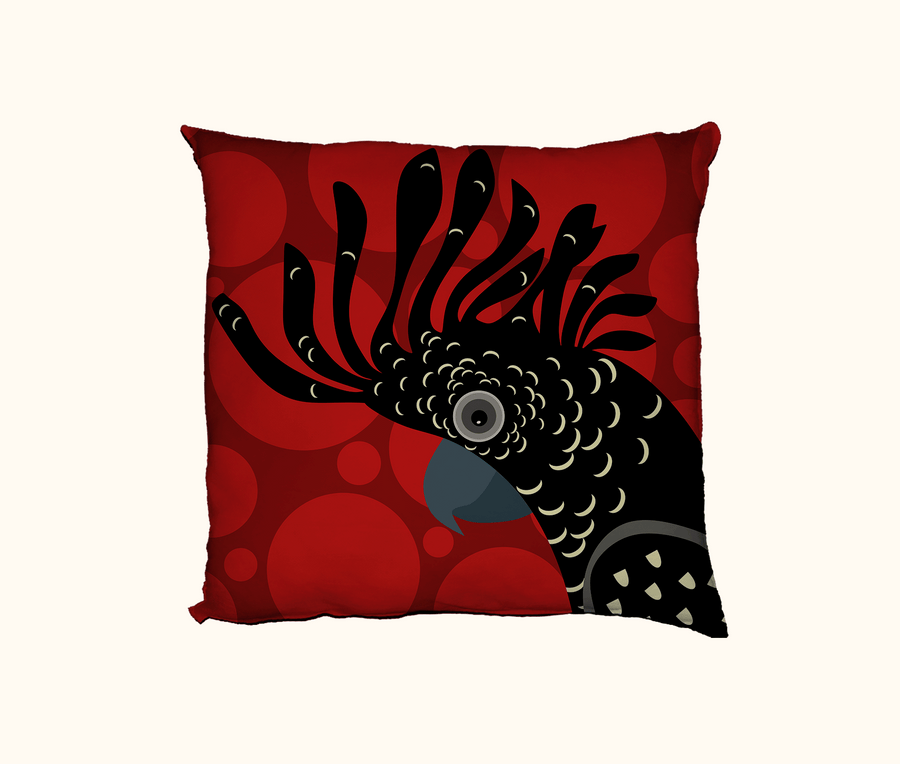 cushion with a stylised red-tailed black cockatoo head on a background of large red spots