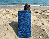Canvas glasses slip case featuring a leafy pattern of deep sea kelp with bubbles in blue propped up on a beach with a pair of glasses poking out the top
