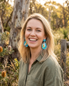 a woman wearing acrylic drop earrings featuring stylised cockatiels, one the right way up and one upside down