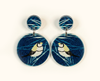 acrylic earrings featuring double-barred finches on a blue background