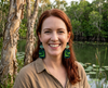 woman wearing acrylic earrings featuring stylised saltwater crocodiles