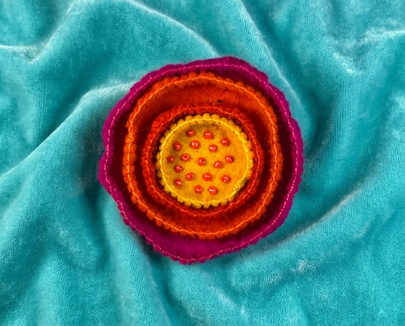 Felt flower brooch with a beaded centre, in yellow, oranges and pink