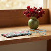 Canvas glasses slip case with a pale blue background and red rosella blossoms and leaves