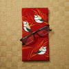 Canvas glasses slip case with stylised double barred finches with red and gold grasses on a red background