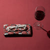 Canvas glasses slip case covered in red mushrooms with white spots on a dark teal green background on a red cloth with a pair of white glasses and a glass of red wine.