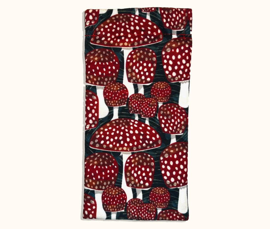 Canvas glasses slip case covered in red mushrooms with white spots on a dark teal green background.