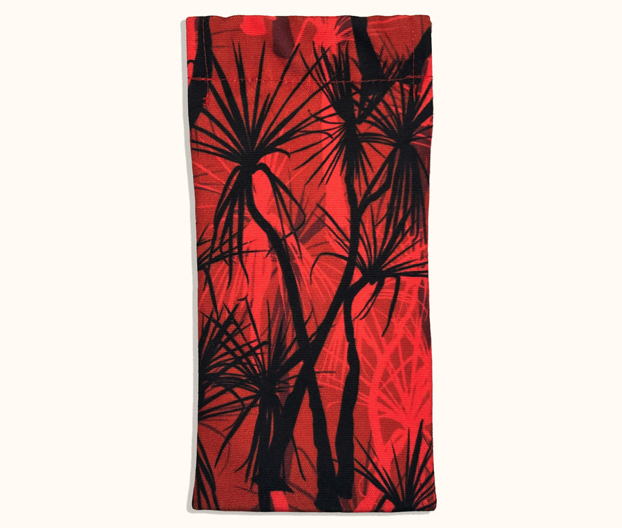 A canvas glasses slip case with a black and red pattern of pandanus trees covering it.