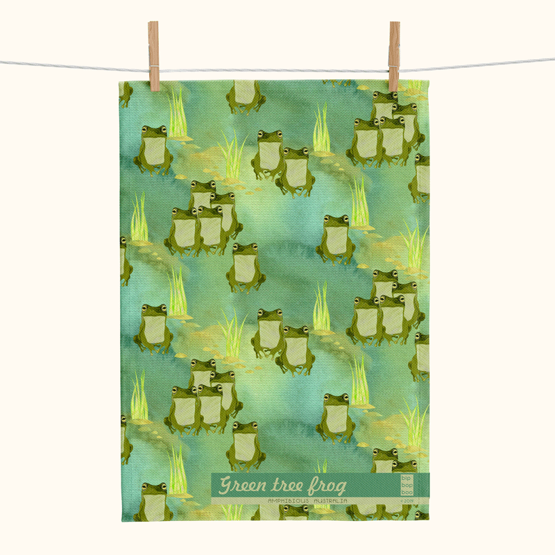 a linen teatowel featuring stylised green tree frogs on a watery green background with some small clumps of grass
