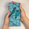 A canvas glasses slip case featuring an illustration of two oriental dollar birds on a blue background with branch patterns.