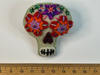 Very pale green sugar skull felt brooch with red and orange eyes and a purple star on the forehead