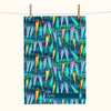 a linen tea towel printed with a pattern of colourful lures against blue and green waves