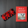 Canvas glasses slip case with black silhouette of brolgas dancing in an art nouveau inspired pattern in hot red and orange tones.