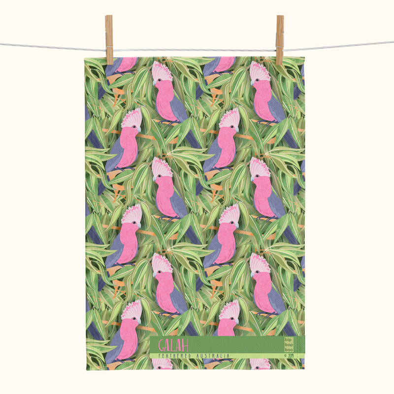linen tea towel printed with an overall pattern of pink and grey galahs against a backdrop of gum leaves