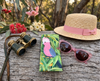 Canvas glasses slip case featuring a galah perched among gum leaves on a log with a pair of pink sunglasses, a sun hat and a pair of binoculars