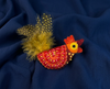 orange and red felt rooster brooch with yellow and black spotty tail feathers