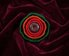 Red and green layered felt brooch with a single flat bead at its centre